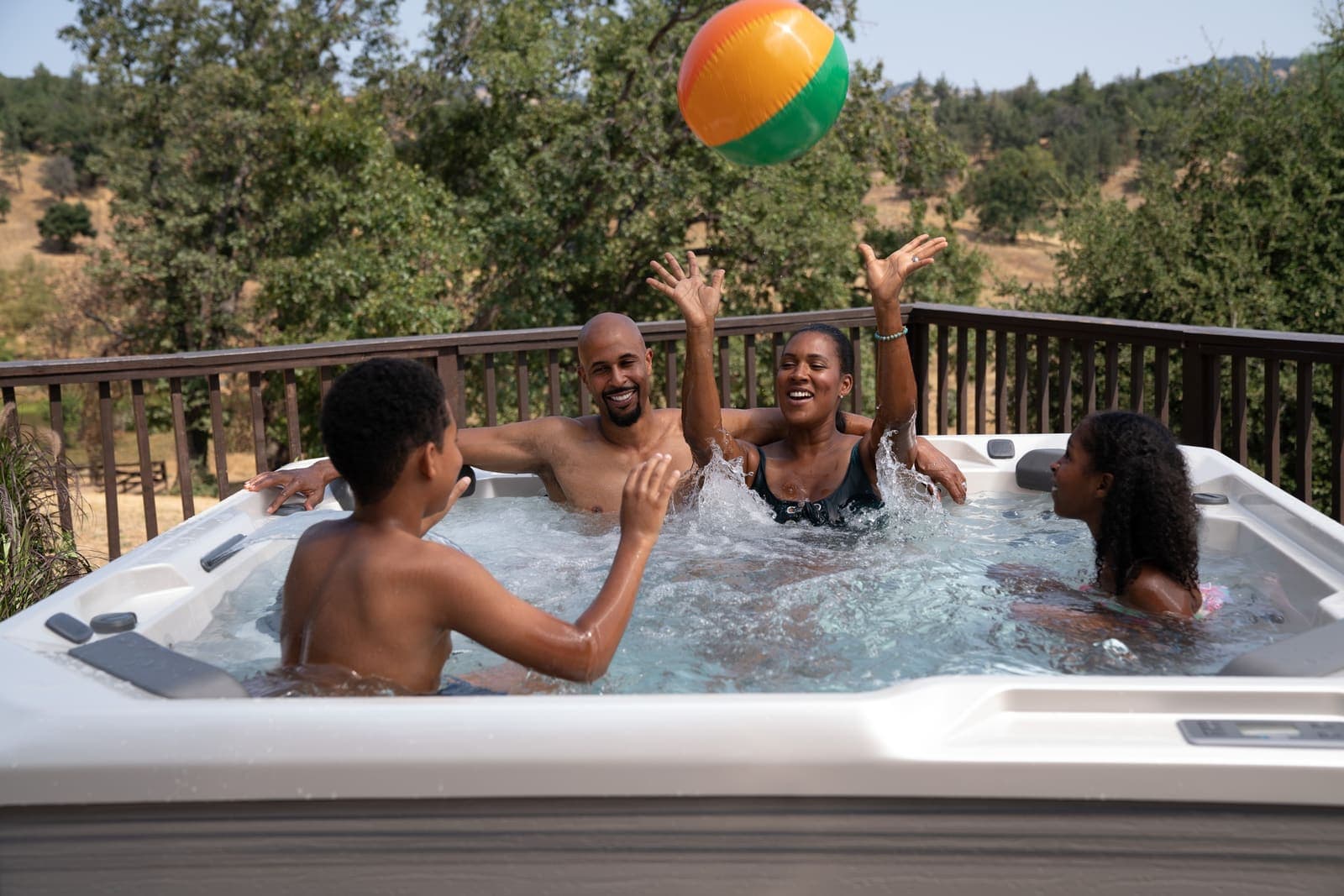 Family playing in a Hot Spot Rhythm hot tub on a summer evening