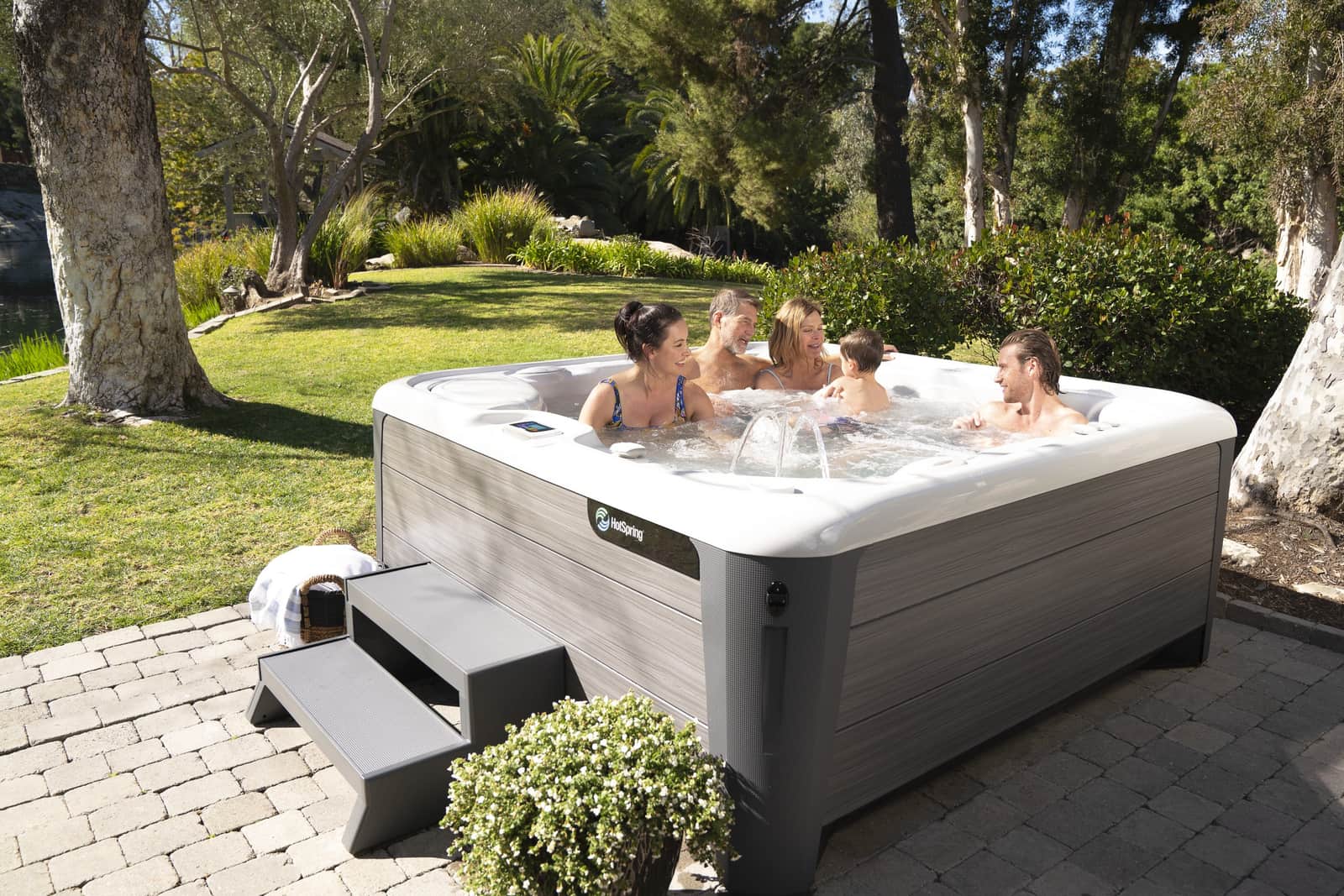 Friends relaxing in a Hot Spring Vanguard hot tub on a stone patio
