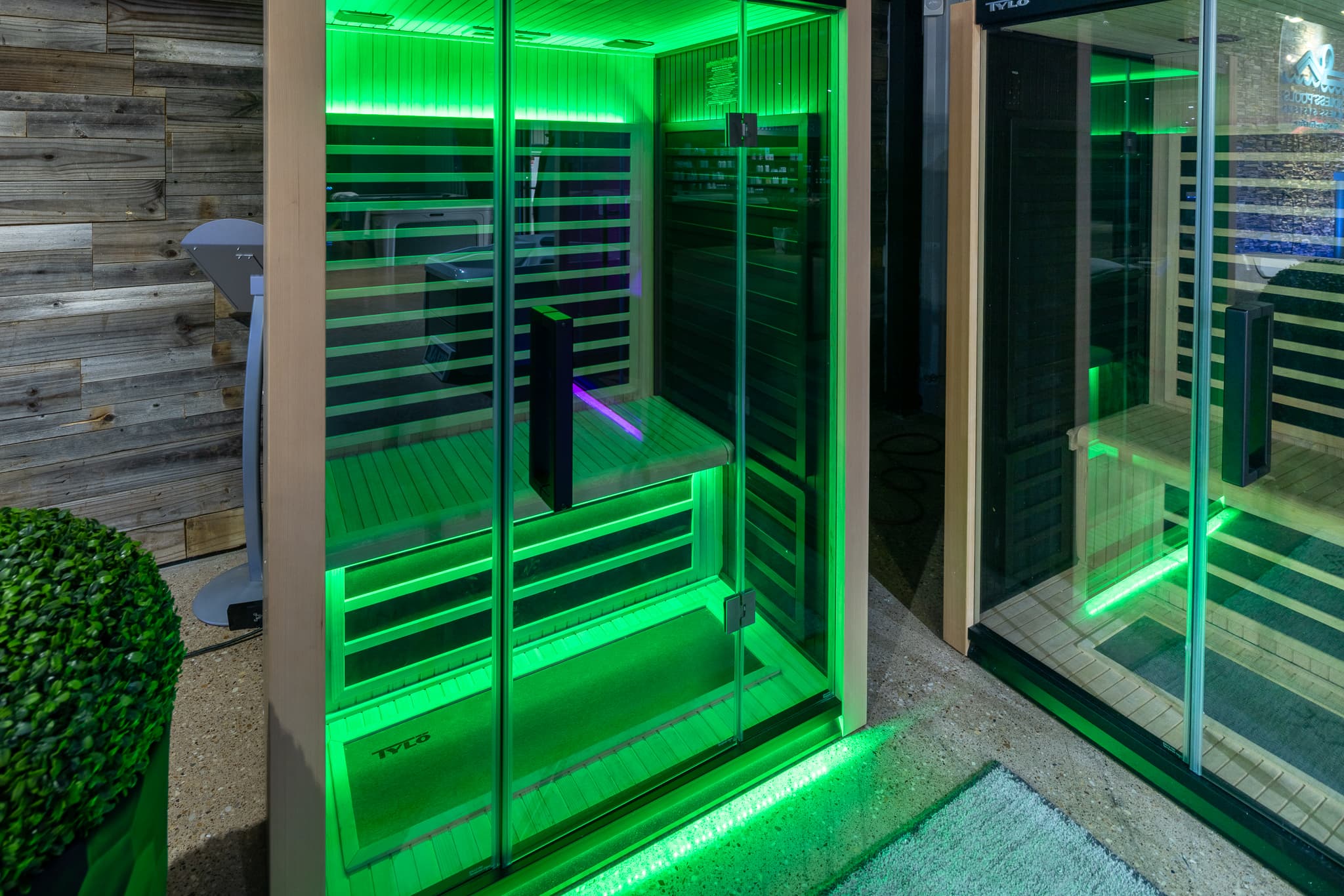 Tylö sauna with the showroom hot tubs visible behind it — the complete contrast therapy setup
