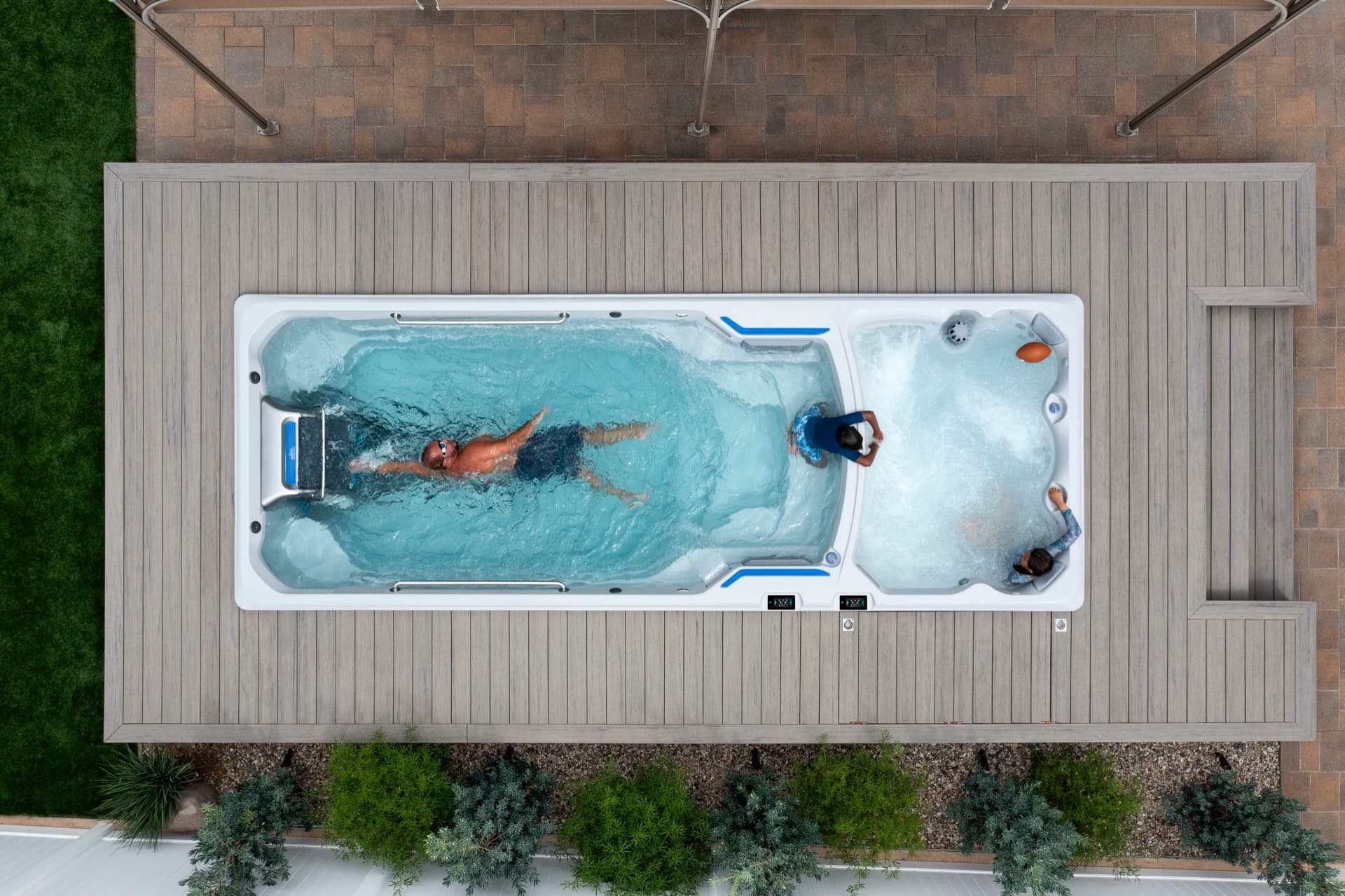 Overhead view of Endless Pools E2000 dual-zone swim spa with a man swimming and a couple soaking in the spa section