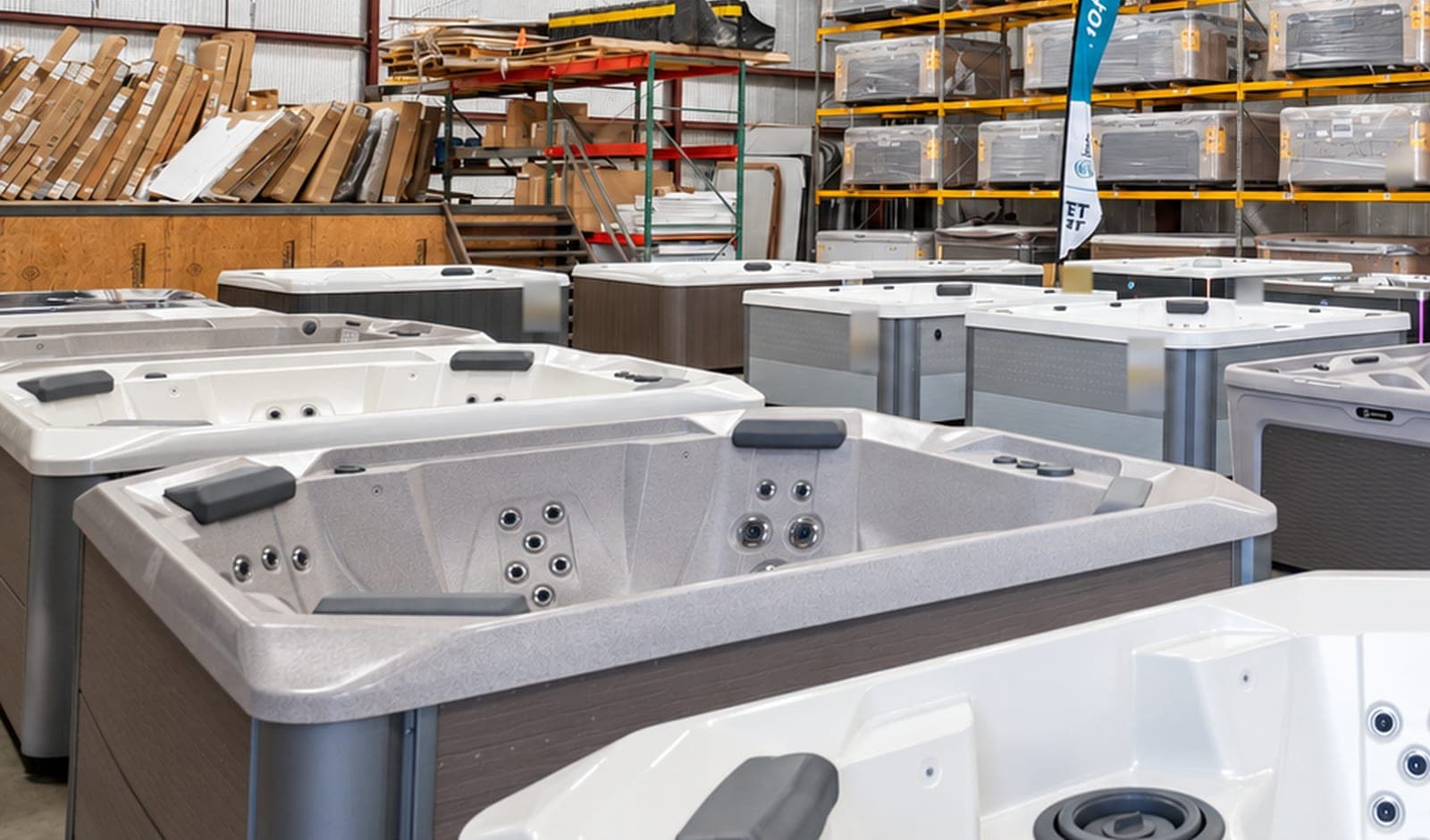 New hot tubs on the floor of our Tyler warehouse, with more still wrapped on the racks behind them