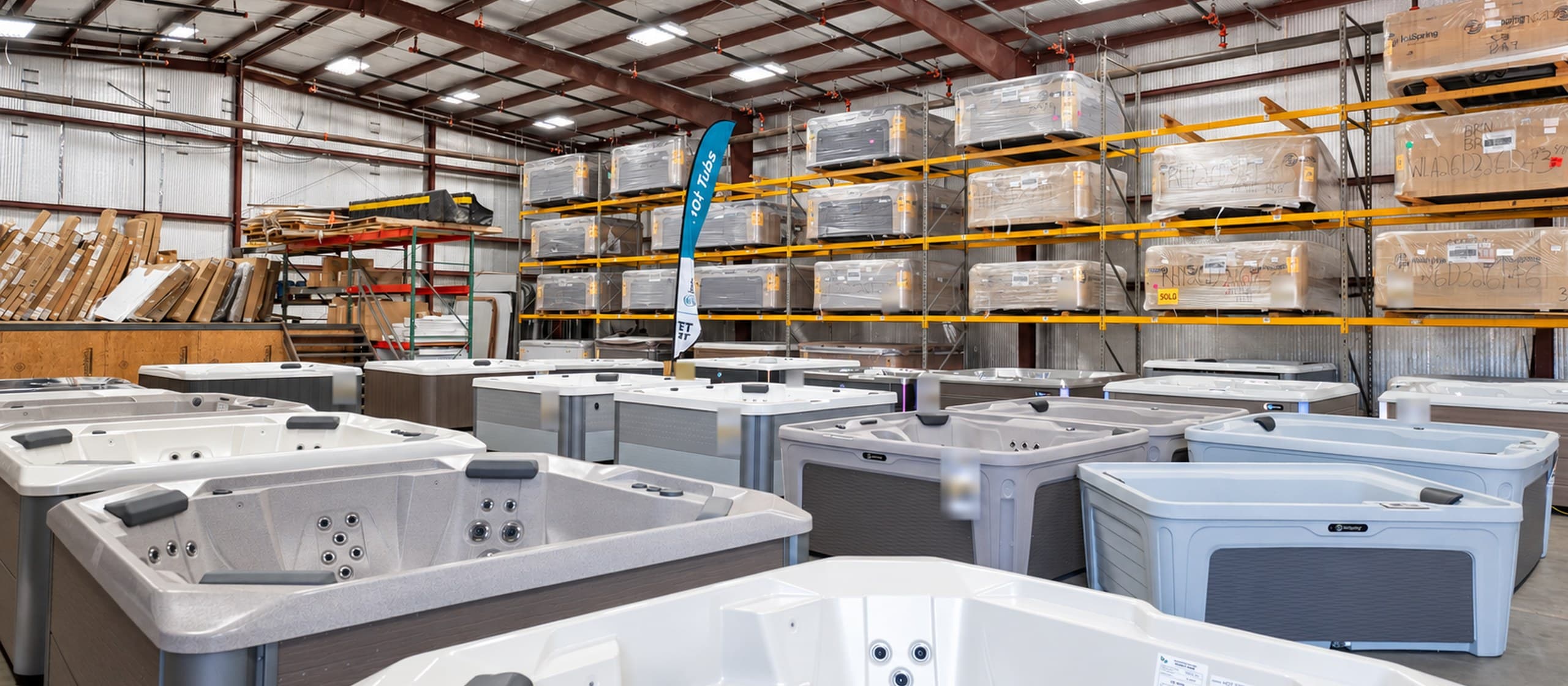 New hot tubs on the floor of our Tyler warehouse, with more still wrapped on the racks behind them